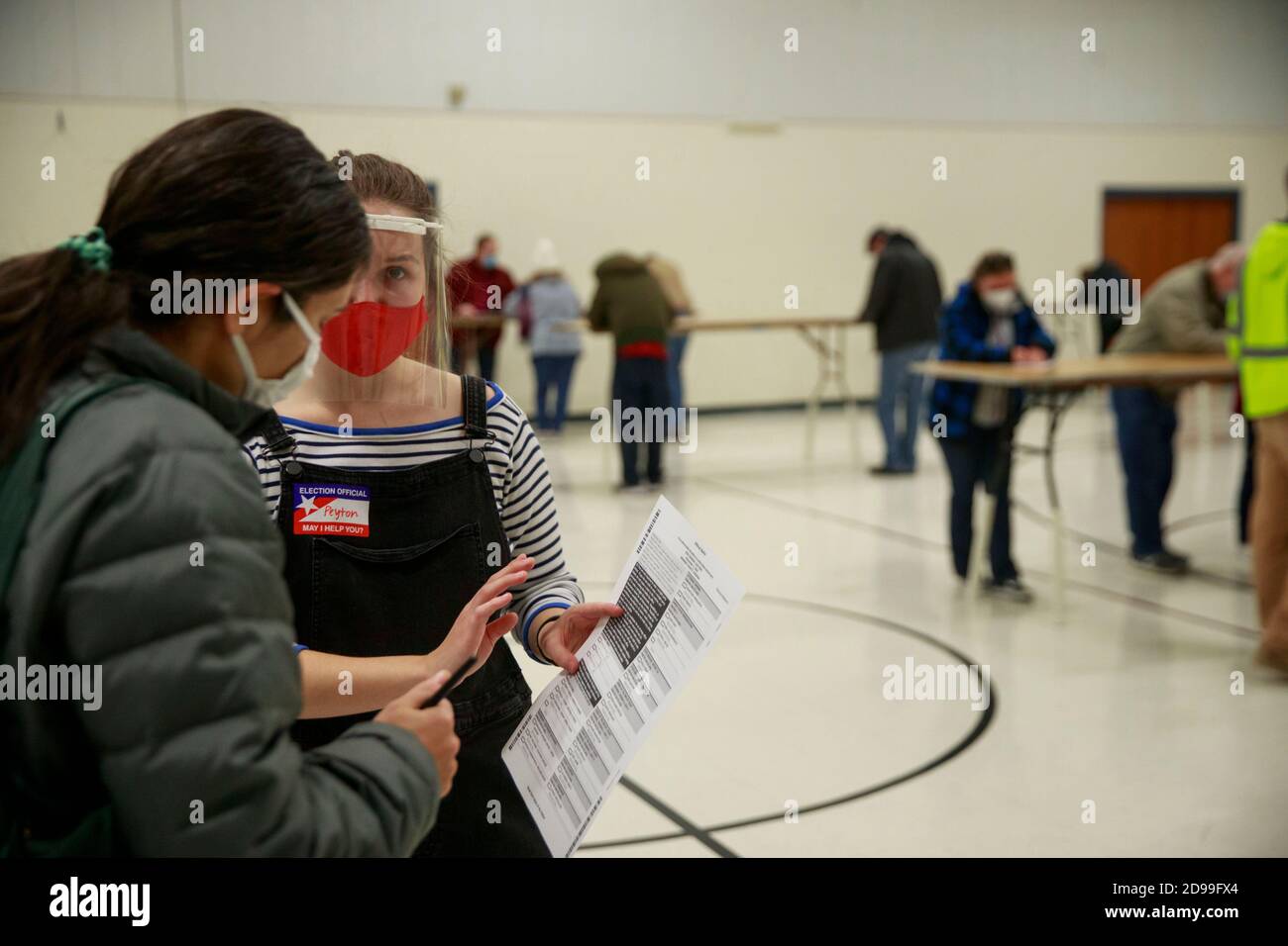 A poll worker speaks to a voter at St. John the Apostle Catholic Church.Polling stations across the United States open for voters to cast their vote for the 2020 presidential election Stock Photo