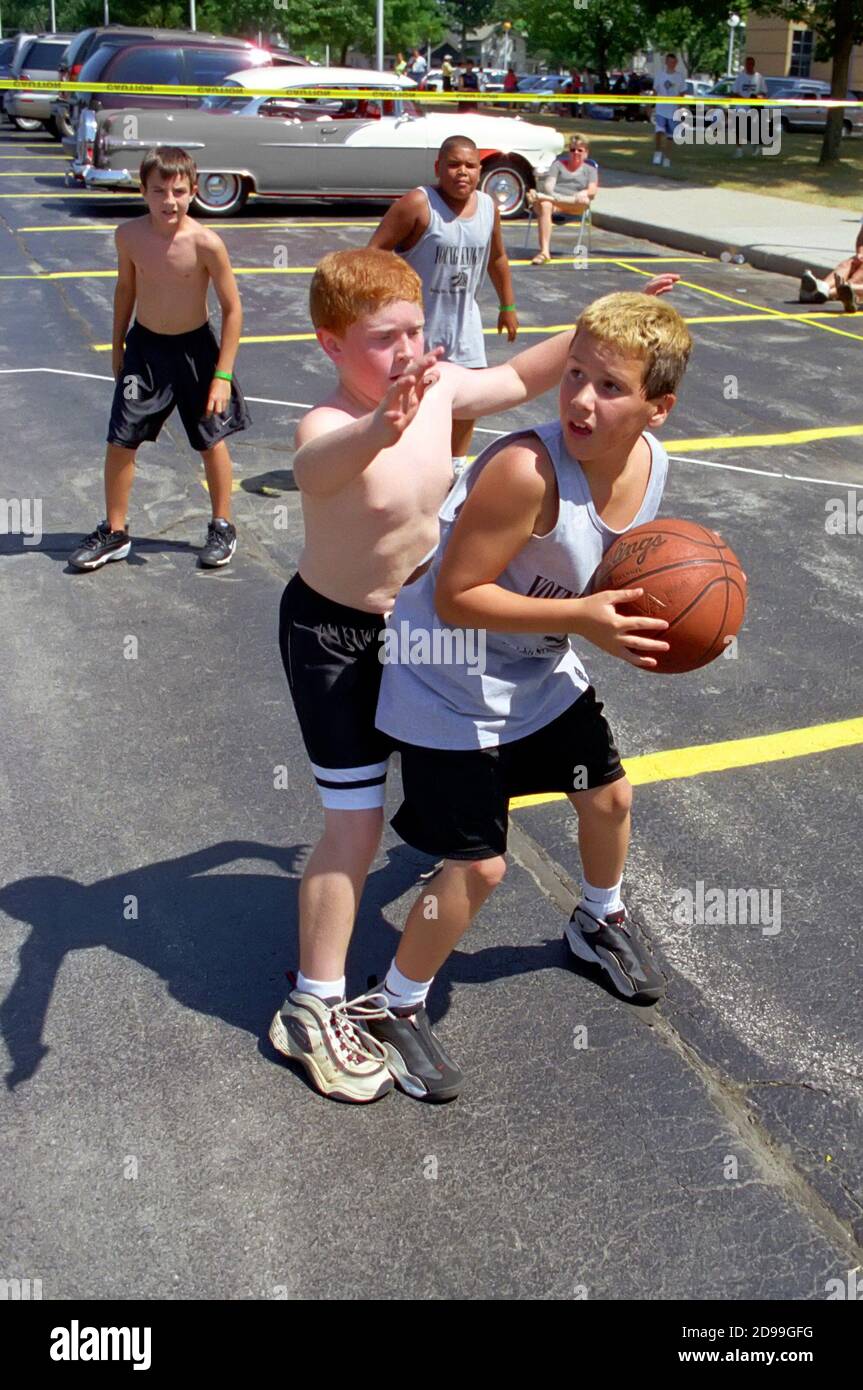 Young Boys male participants play 3 on 3 basketball outdoors Stock Photo