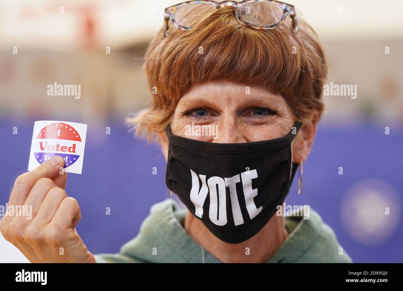 Olivette, United States. 03rd Nov, 2020. Poll worker Heather Huewe wears a  VOTE mask holding a "I Voted Today" sticker as she works at the Old Bonhomme  School in Olivette, Missouri on