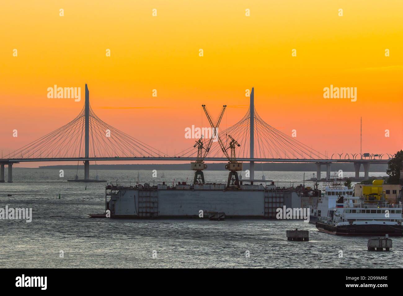 cable-stayed bridge over the river and floating dock at sunset Stock Photo