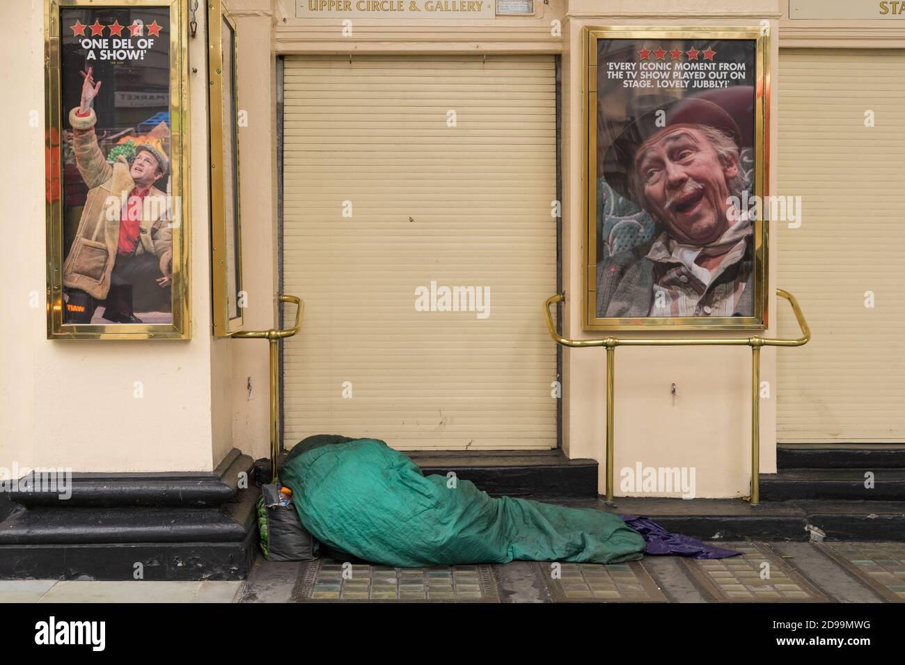 Homeless person sleeping in a sleeping bag on the steps outside a closed theatre. London Stock Photo