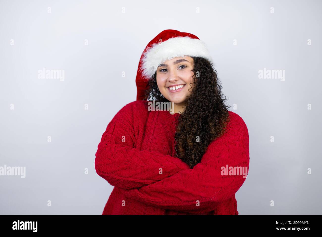 Young beautiful woman wearing a Santa hat over white background with a ...