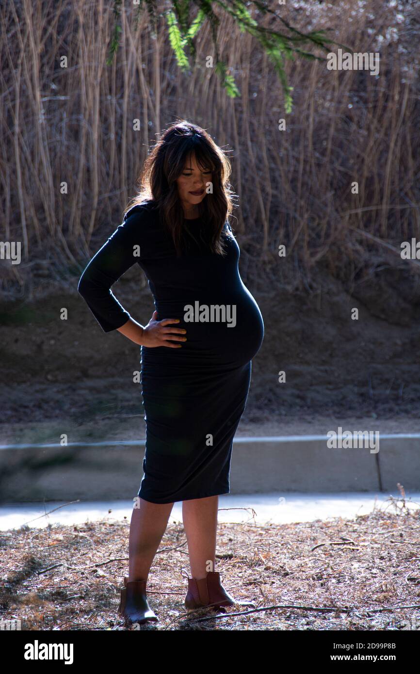 A pregnant woman standing at a park. Stock Photo