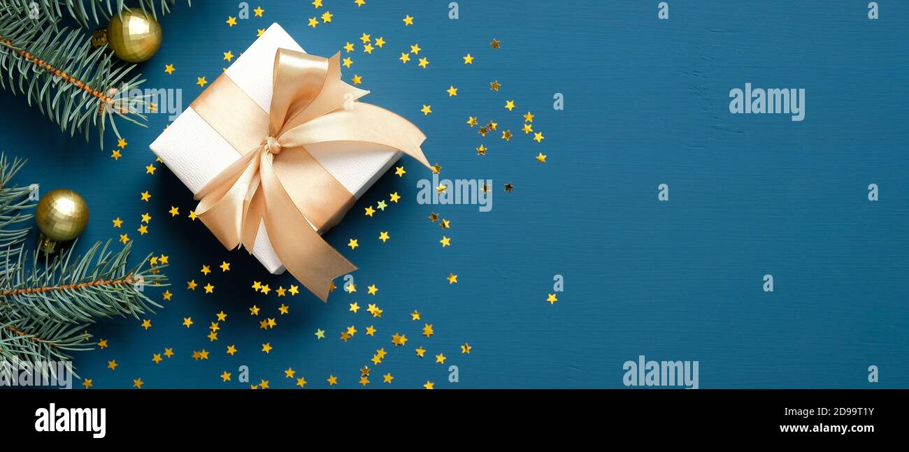 Gifts Header Christmas gift box with golden ribbon bow, fir branches, confetti on ...