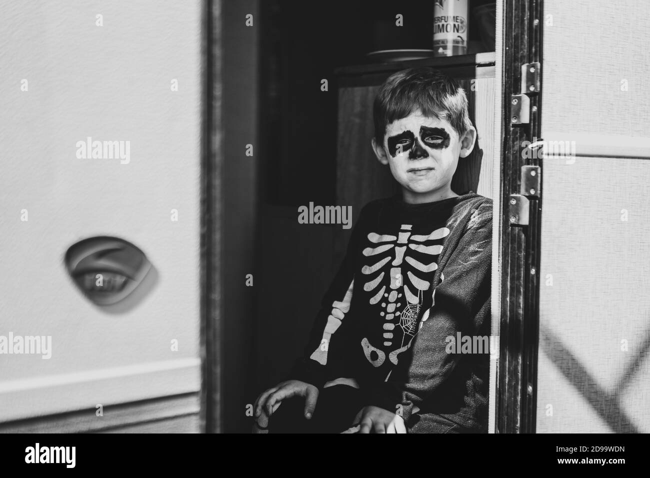 Grayscale shot of a cute little boy wearing a Halloween skeleton costume Stock Photo