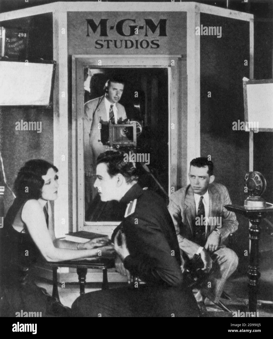 1930 , USA  : Nils Aster ( 1897 - 1981 ) and Raquel Torres at MGM Studios during a early recording sound for a talkies movie . The microphone was beside the actors, over the glass  window stand the cameraman John Arnold for eliminate all sounds of camera - CINEMA SONORO - SILENT MOVIE to TALK - Metro Goldwyn Mayer - MGM - M.G.M. - MUTO - TALKIES  - MICROFONO - SET - CINEMA - FILM -----  Archivio GBB Stock Photo