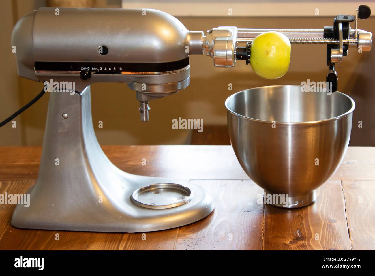 https://c8.alamy.com/comp/2D99YF8/a-mixing-stand-with-a-peeler-attachment-sitting-on-a-wooden-table-with-a-yellow-apple-getting-ready-to-be-peeled-2D99YF8.jpg
