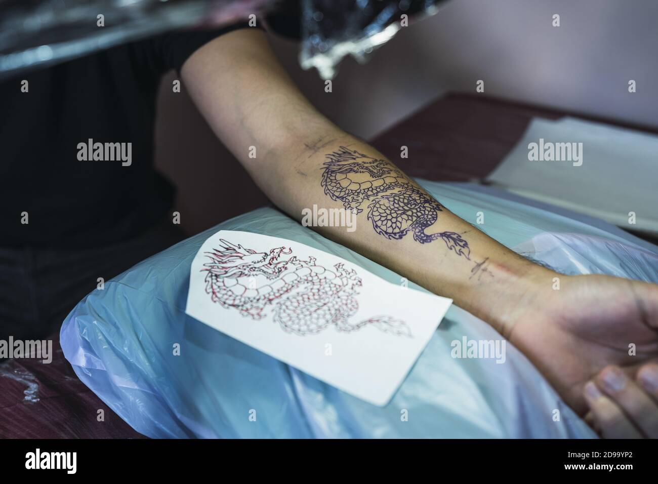 Dragon tattoo on a man's hand and a tattoo paper next to it Stock Photo -  Alamy