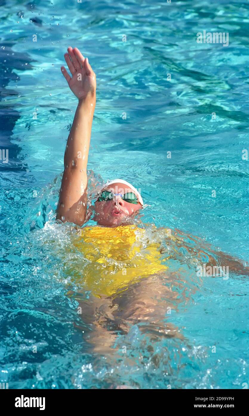High school swimming meet includes backstroke competition between male and female swim contestants Stock Photo