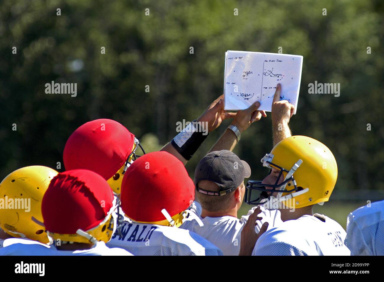 High School Football has coash pointing to play book during a practice session Stock Photo