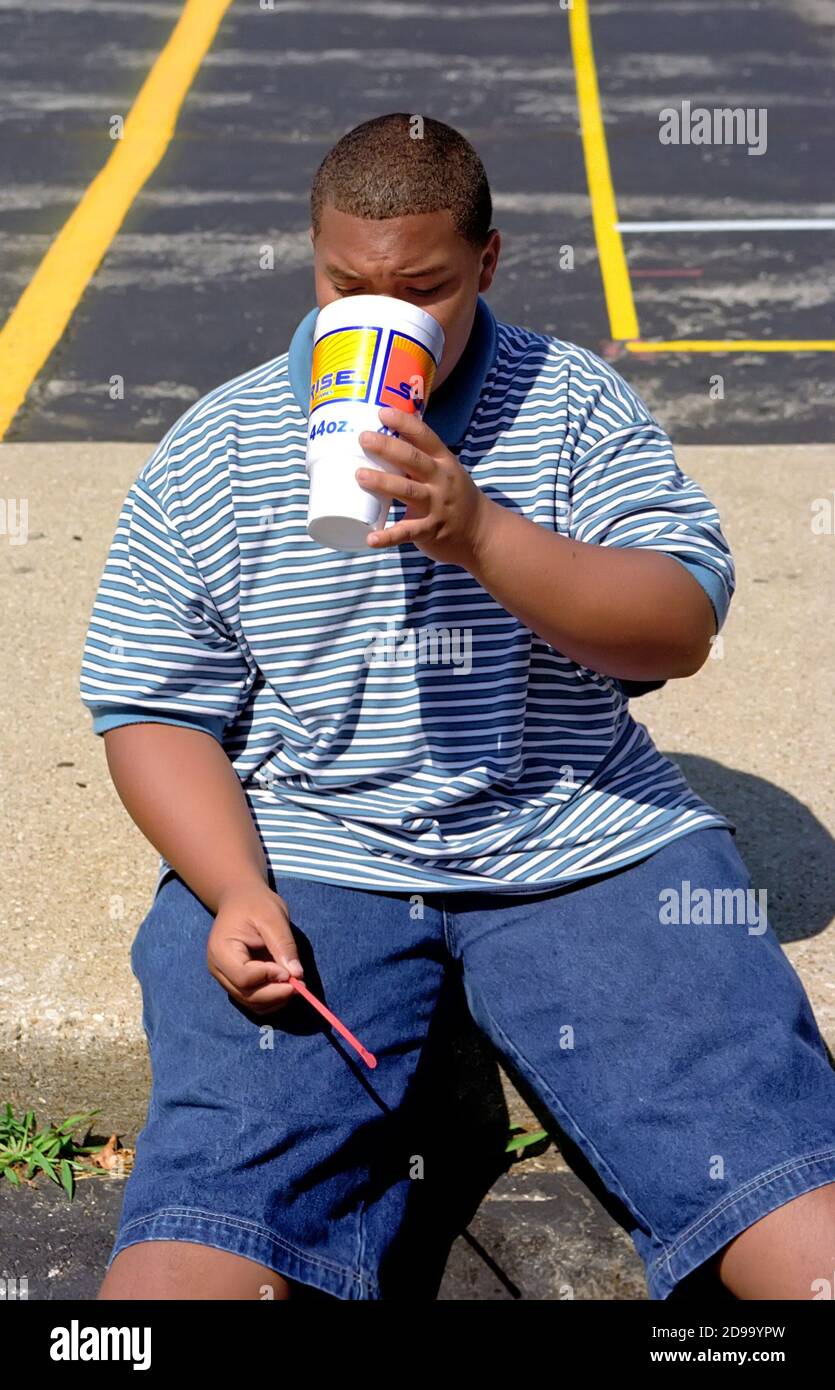 Overweight teen male drinks a high calorie content soda pop Stock Photo