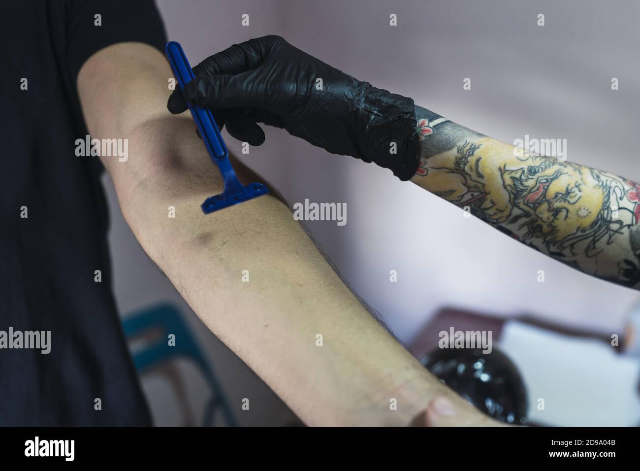 Tattoo artist shaving the hand of a man before tattooing Stock Photo