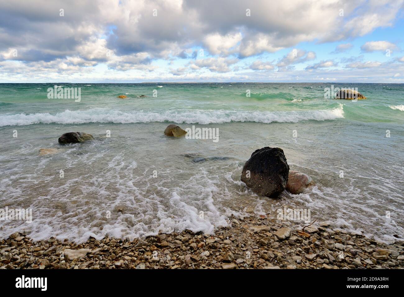 Mackinaw City, Michigan, USA. Waves and swirling water relentlessly move toward a rocky shoreline of Lake Michigan in the Straits of Mackinac. Stock Photo