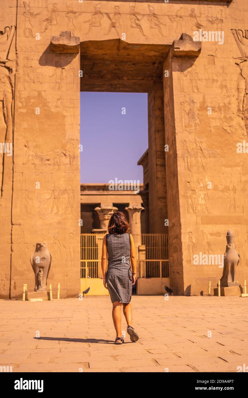 Vertical shot of a female wearing a dress and walking around The Temple of Horus at Edfu, Egypt Stock Photo