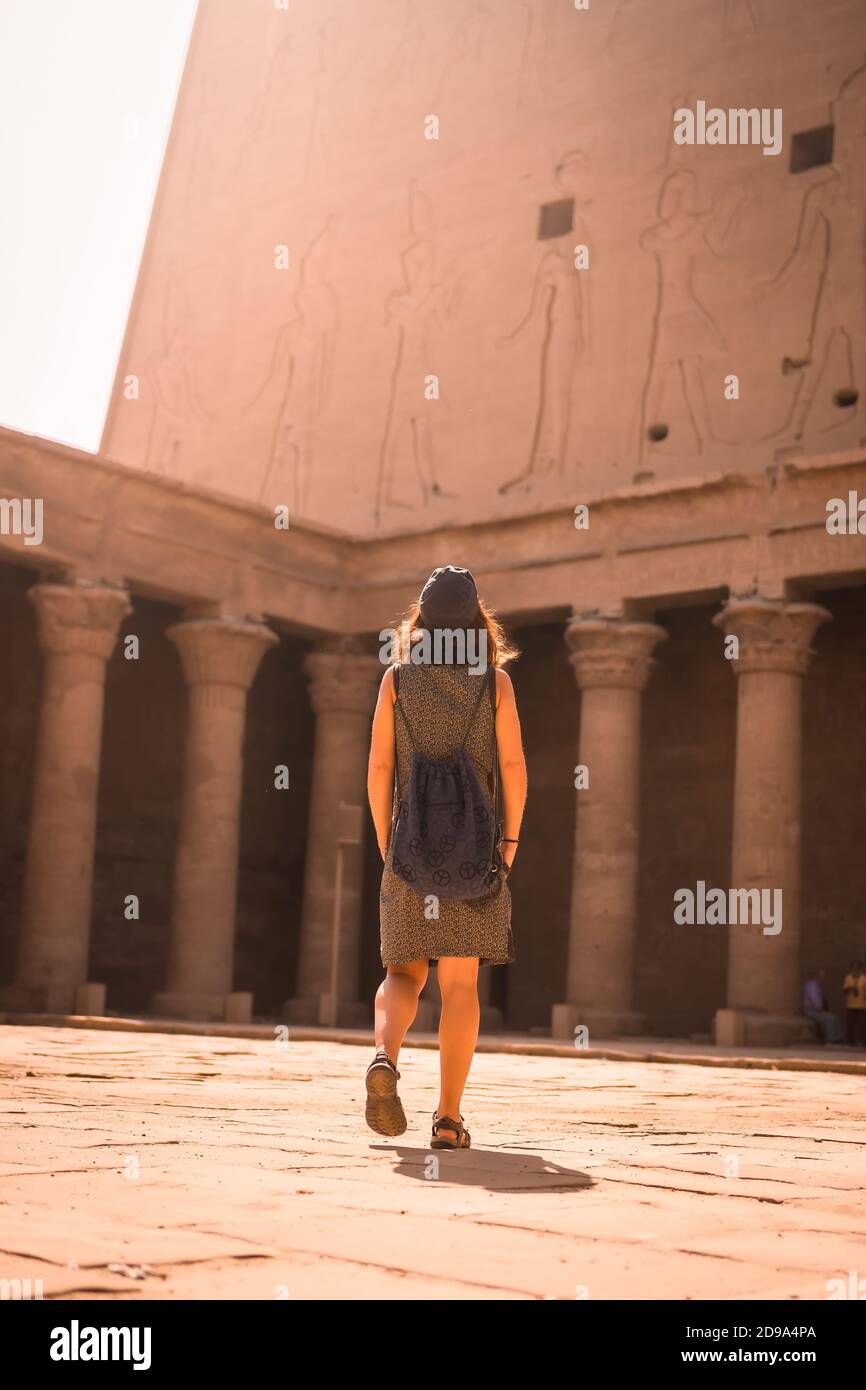 Vertical shot of a female wearing a dress and walking around The Temple of Horus at Edfu, Egypt Stock Photo