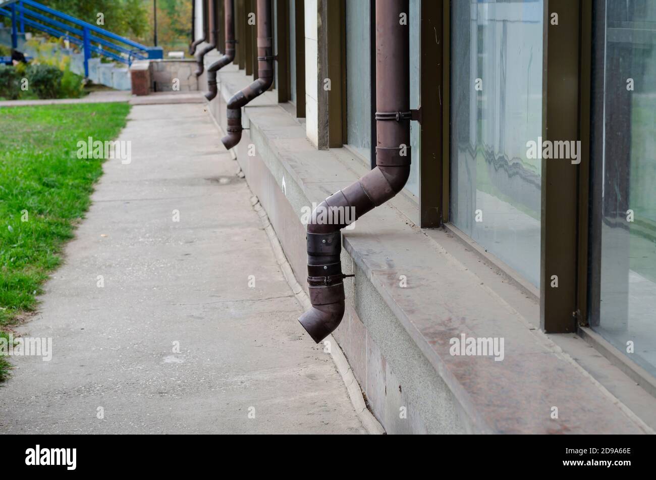 Facade of building with attached brown gutters. Row of plastic rain