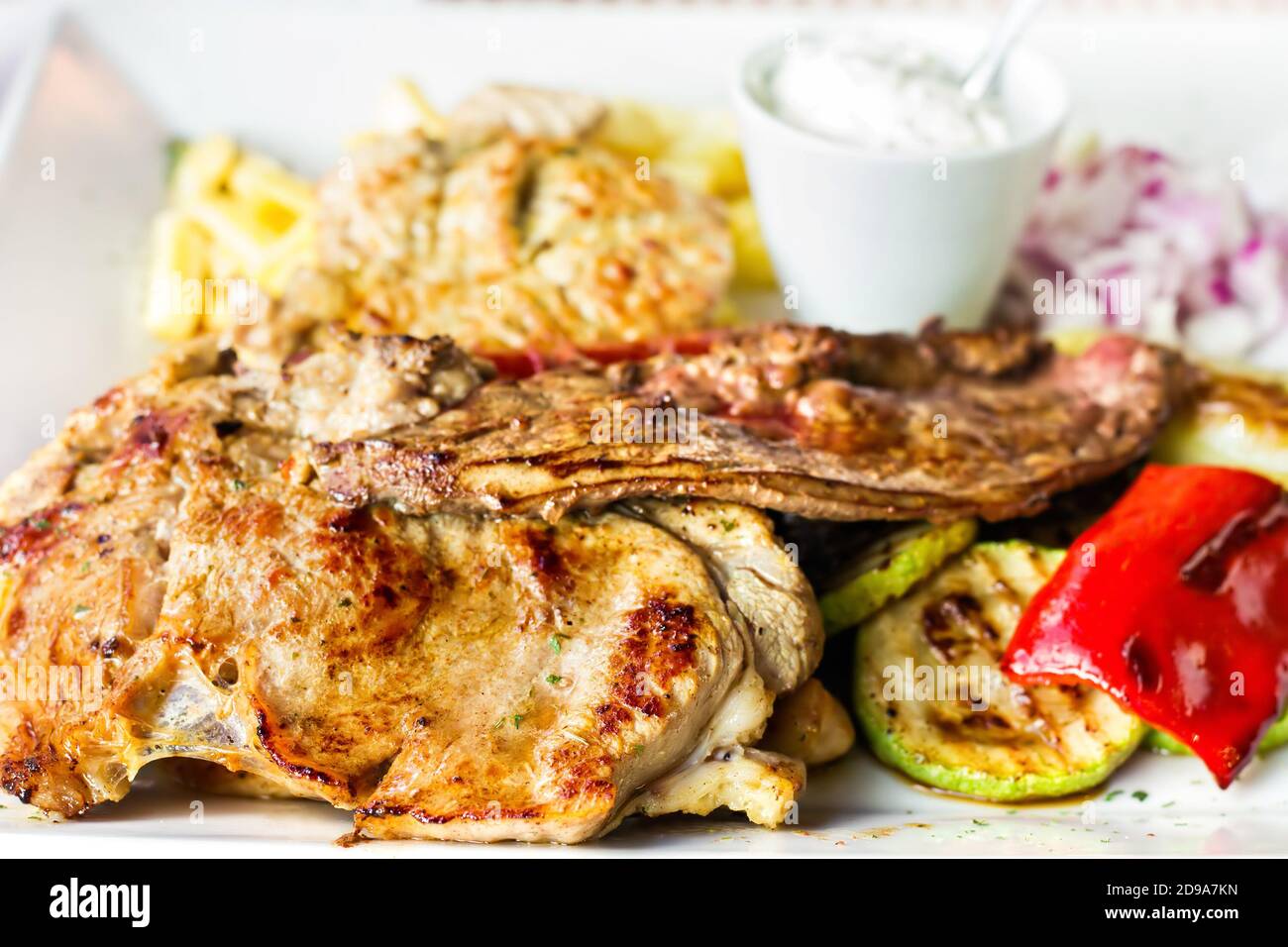 Traditional Balkan mixed grill dish - different types of bbq meat and vegetables with fries, selective focus Stock Photo