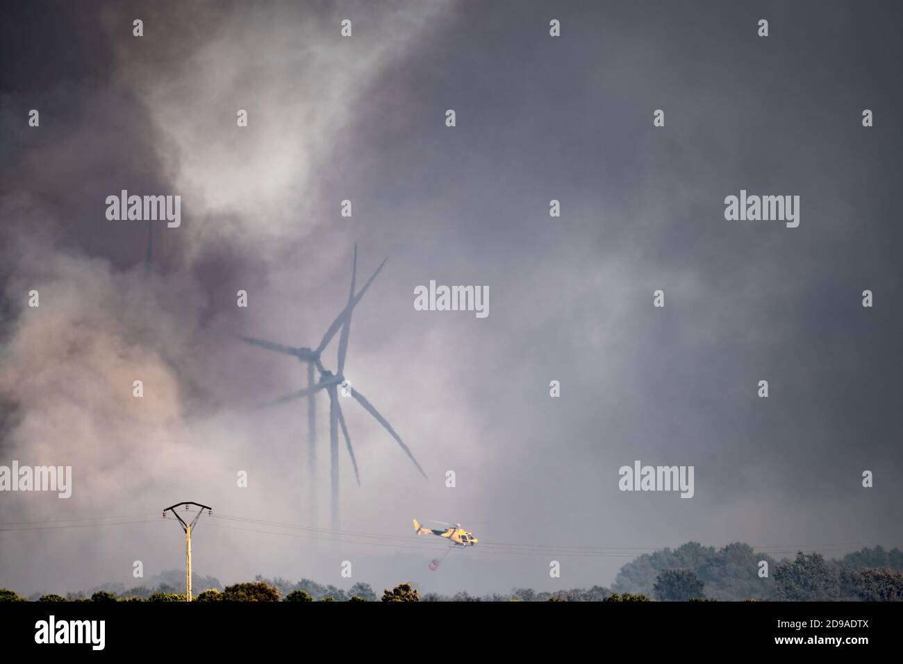 Smoke, windmills and helicopter flying with bambi-bucket Stock Photo