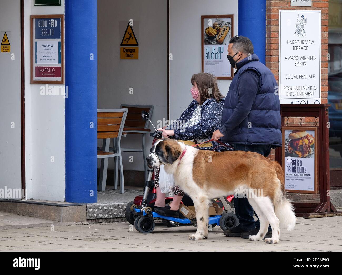 MAN AND WOMAN WITH DOG AND INVALID SCOOTER OUTSIDE A PUBLIC HOUSE. Stock Photo