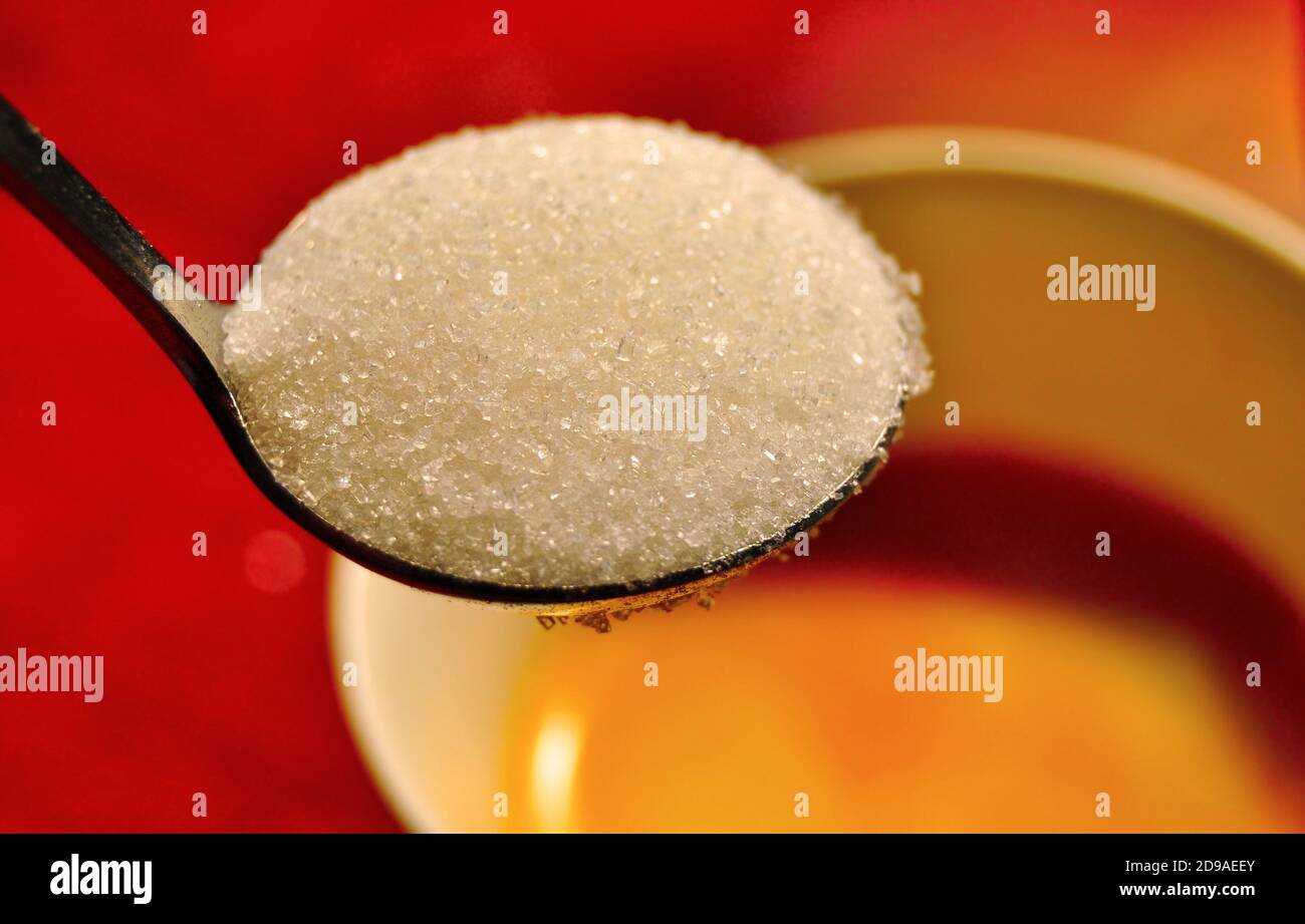 A teaspoon full of white sugar above the coffee cup, health concept ...