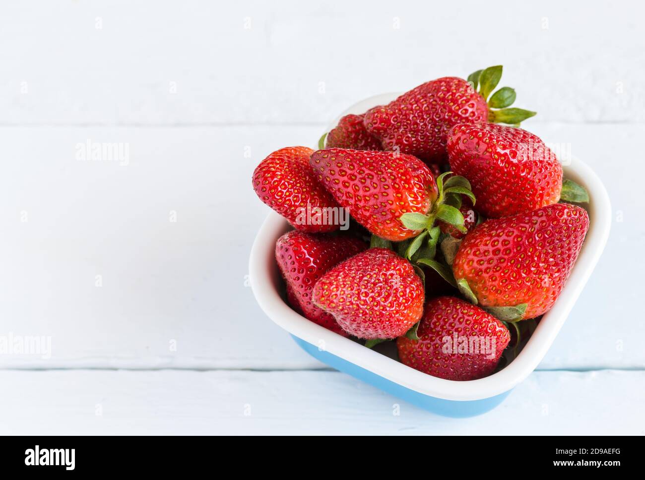 Fresh farm strawberries in a bowl isolated on rustic wooden white ...