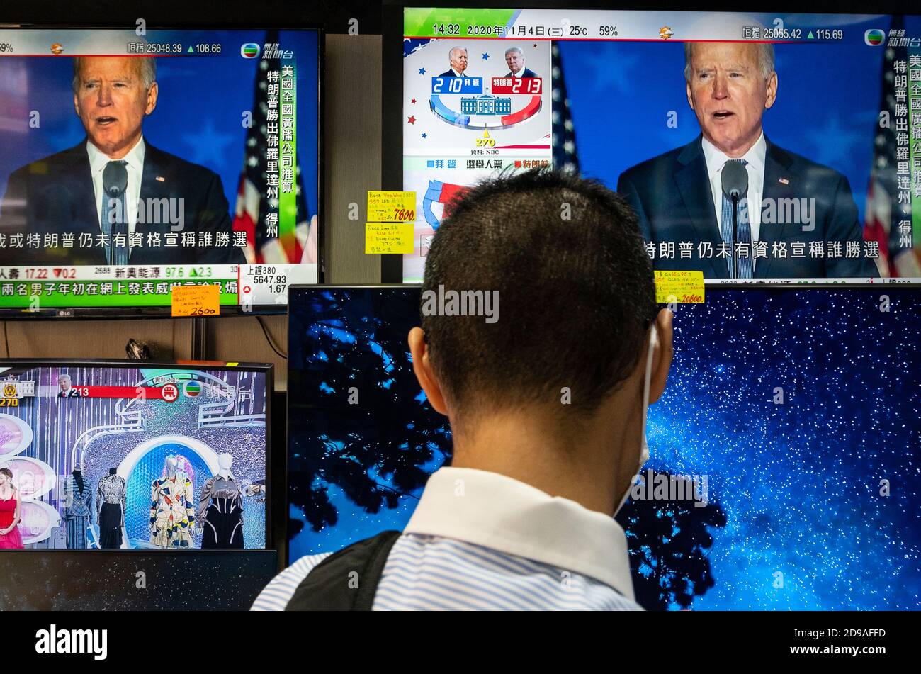 A customer at an electronic goods store,  looks at television screens for sale showing the live news report about the US presidential election. Stock Photo