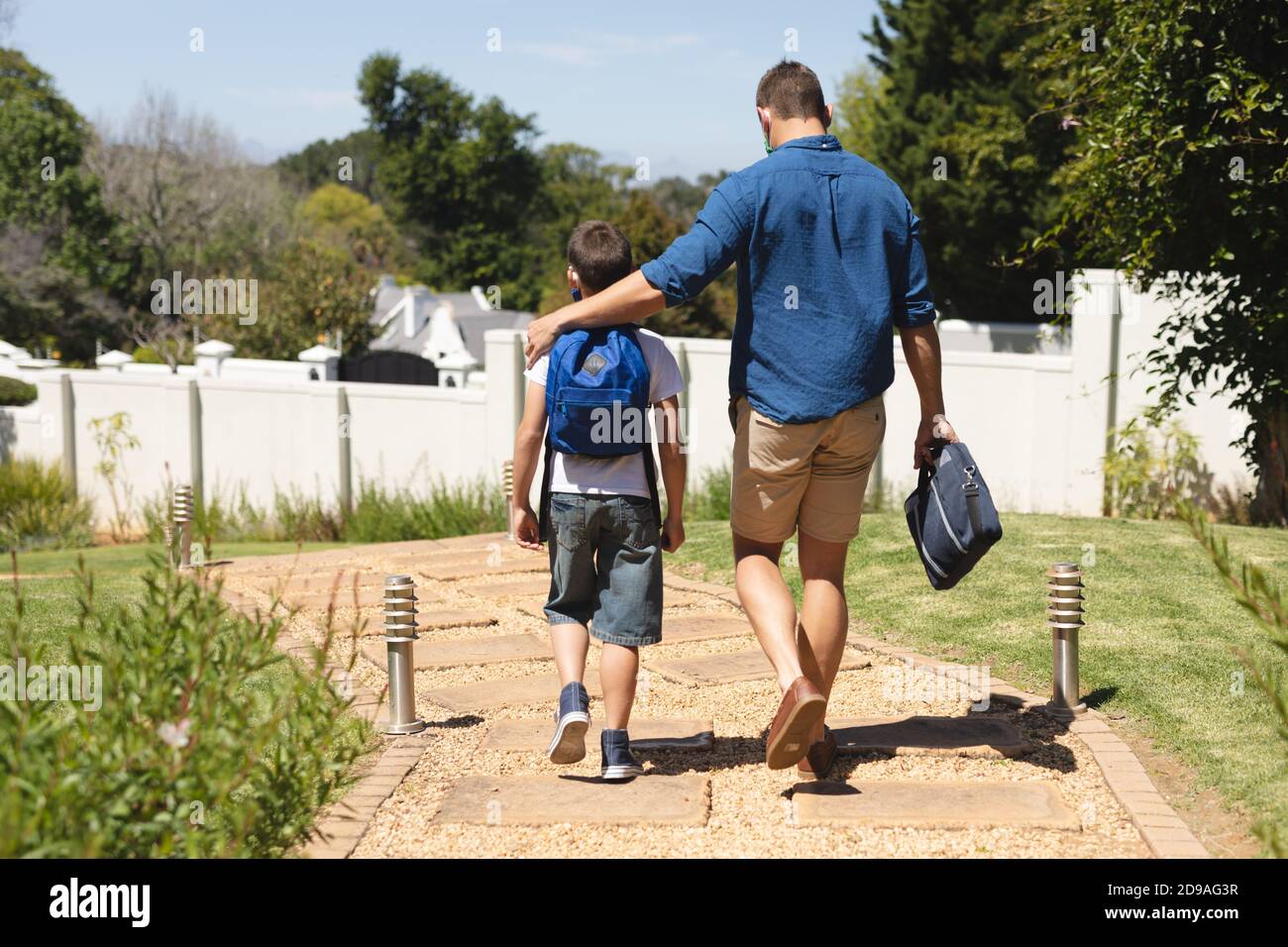 Caucasian boy carrying schoolbag walking to school with his father and schoolbag Stock Photo