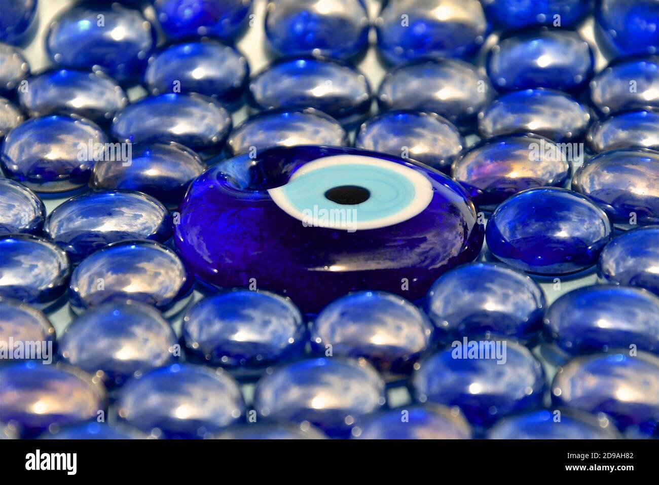 A side perspective view of shiny irridescent blue glass beads with a central peacock design bead Stock Photo