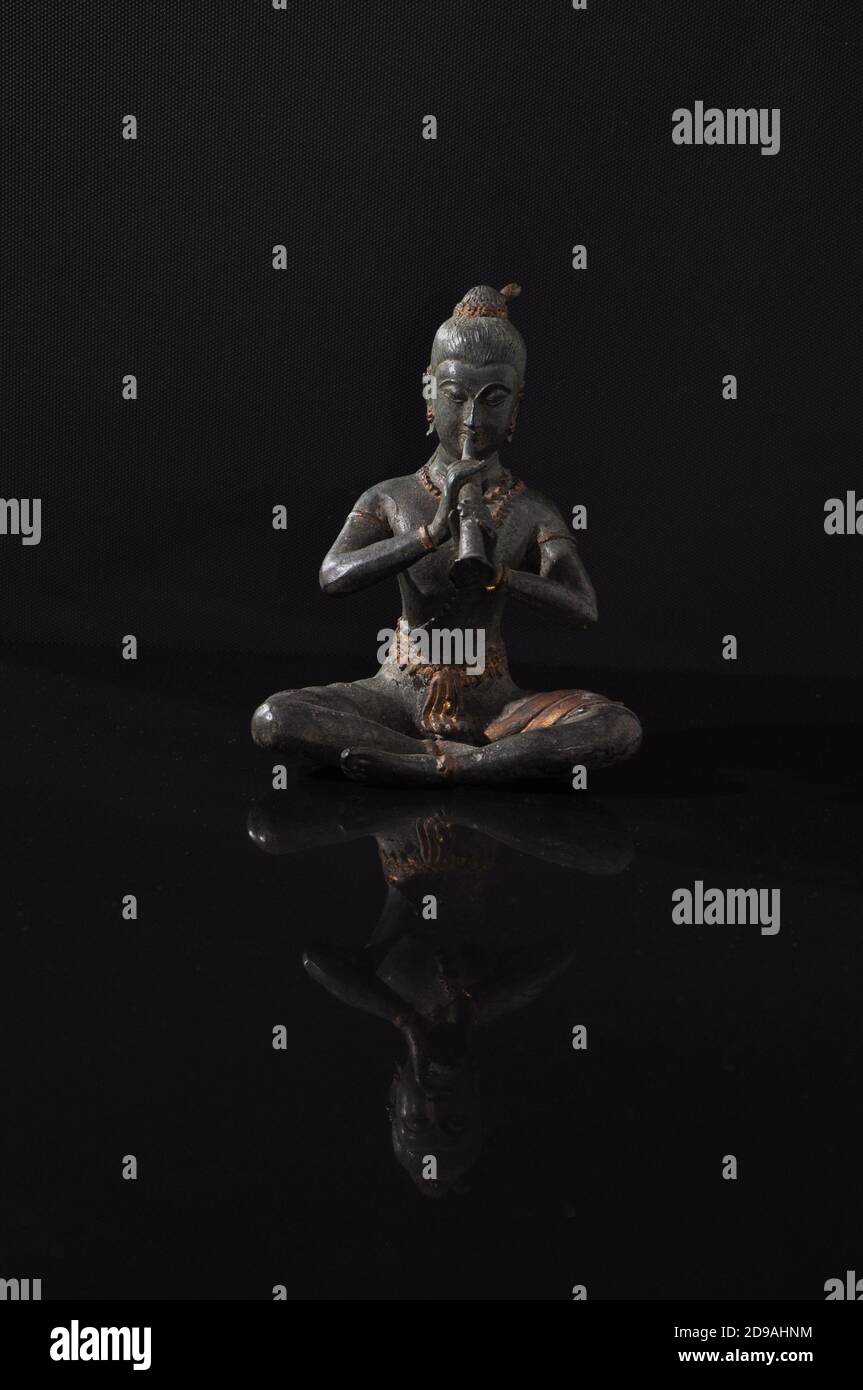 Bronze buddha statue on a black reflective surface with an inverted