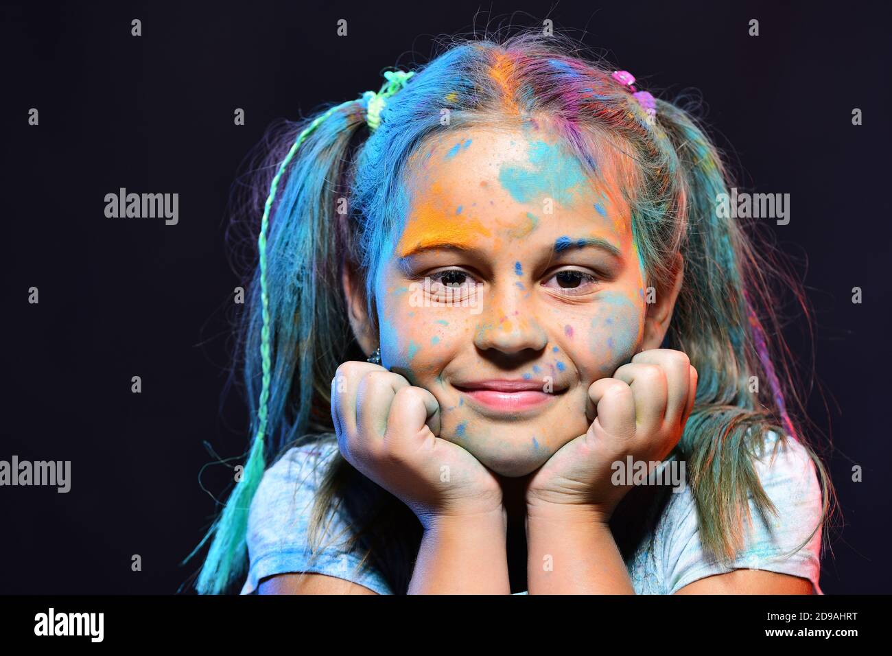 Children and creativity concept. Schoolgirl has paint spots on face