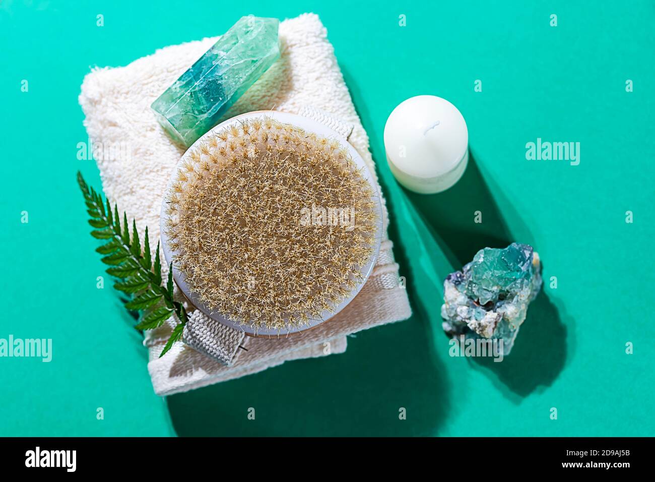 Natural organic wooden body massage brush, crystals, towel, fern leaves with natural sunlight. Home Spa Therapy. Stock Photo