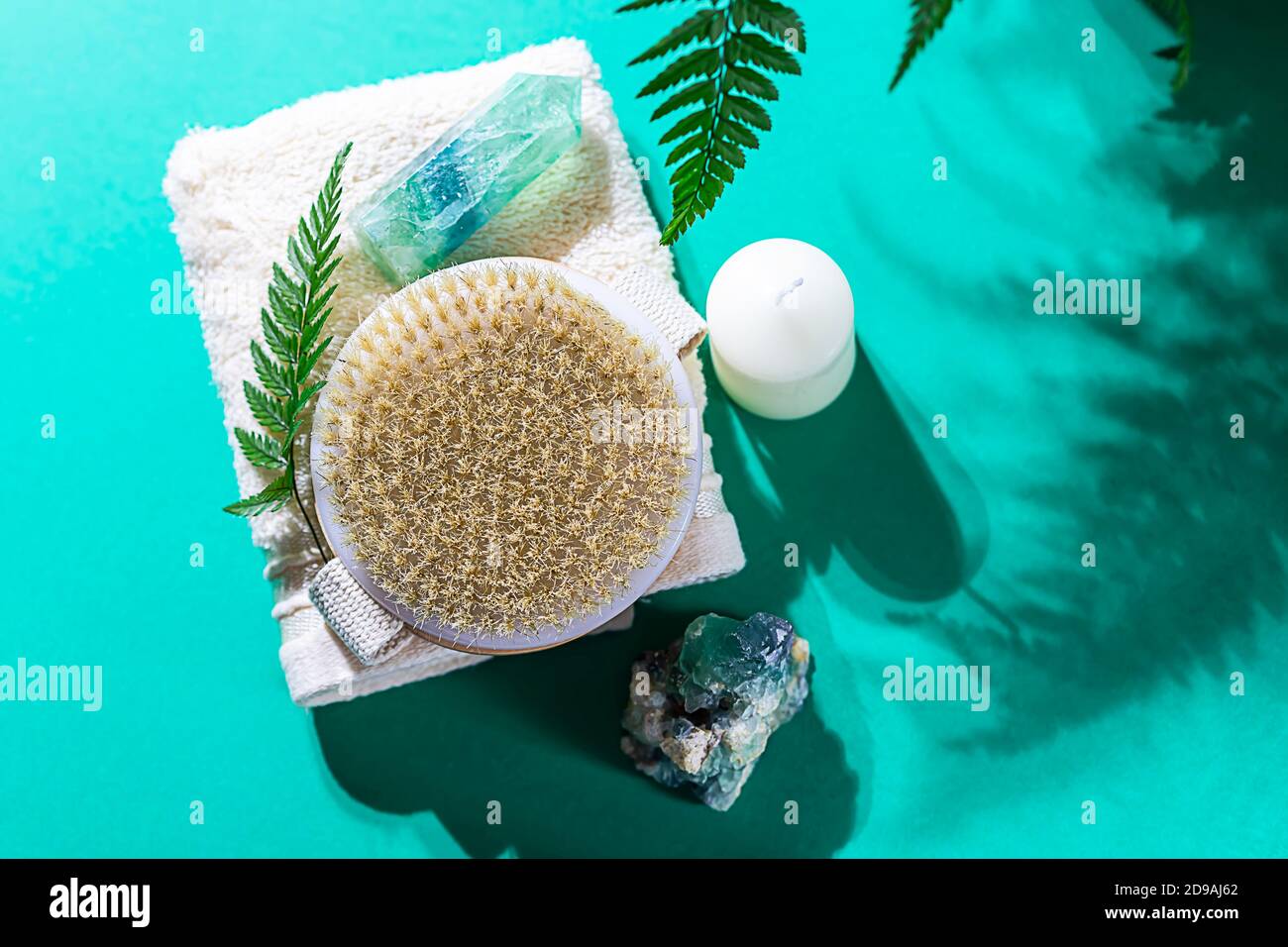 Natural organic wooden body massage brush, crystals, towel, fern leaves with natural sunlight. Home Spa Therapy. Stock Photo