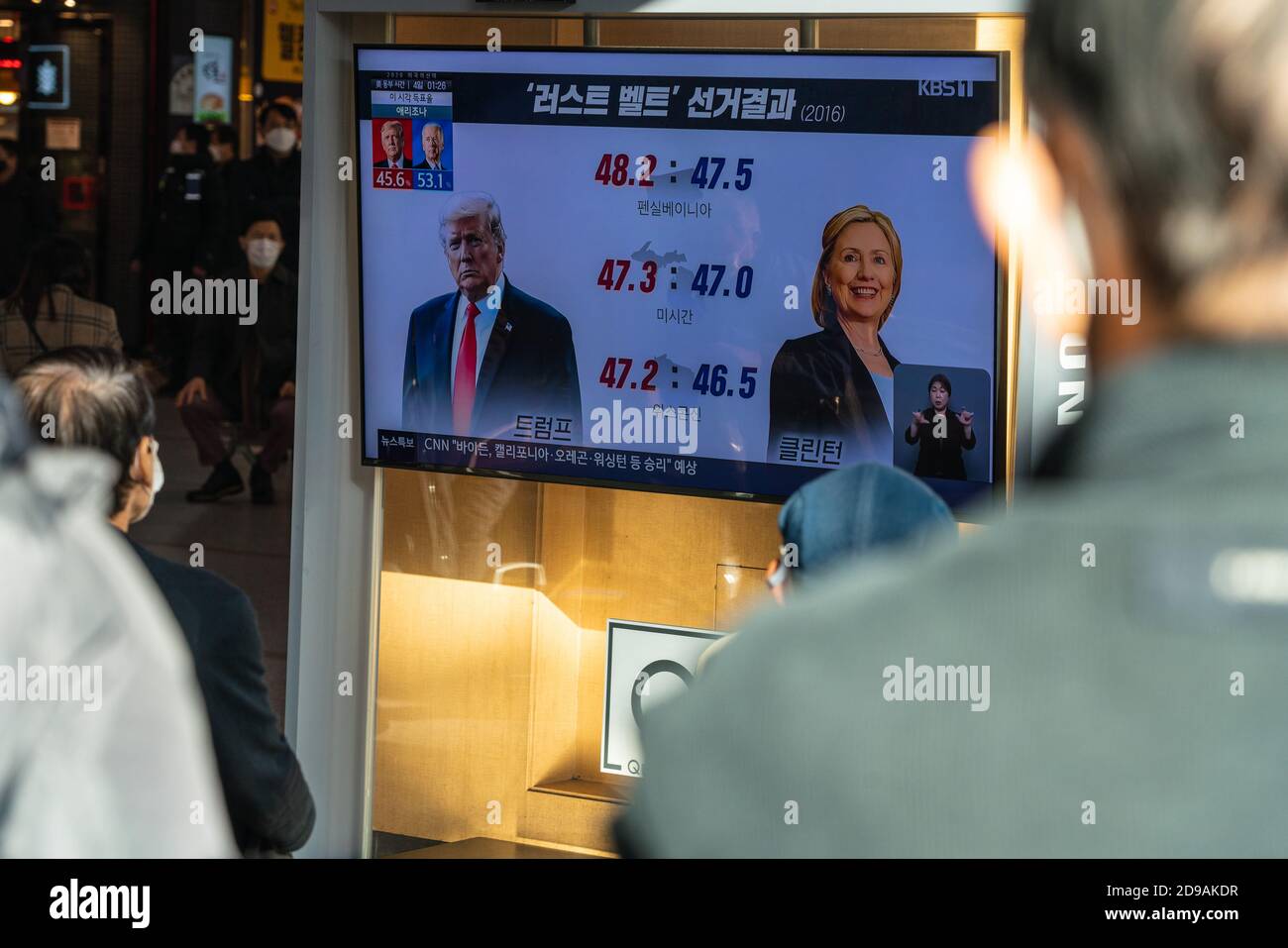 People at Seoul Train Station watch news report about the US presidential election comparing Hillary Clinton with Donald Trump on 2020 US presidential election day.. Stock Photo