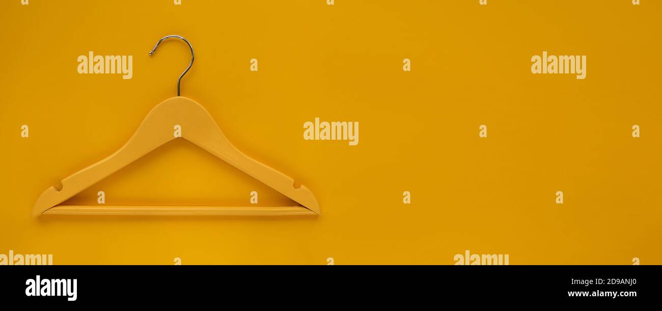 Wooden Coat hanger with black paper label isolated on yellow paper background. Clothing tag, label blank mockup template, to place your design. Black Stock Photo