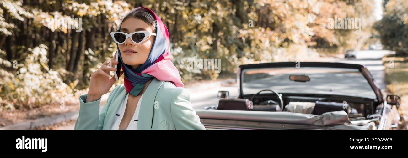 Fashionable woman talking on smartphone during car trip on road, banner Stock Photo