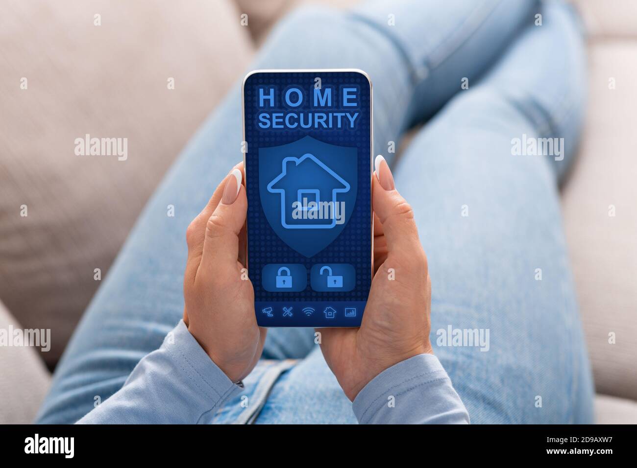Woman using her smartphone with home security application Stock Photo