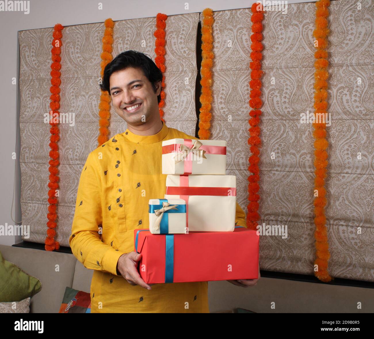 Young happy Indian man wearing traditional  holding gift boxes. Stock Photo