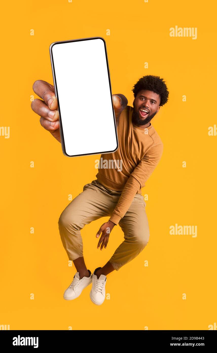 Excited black guy holding smartphone, jumping up Stock Photo - Alamy