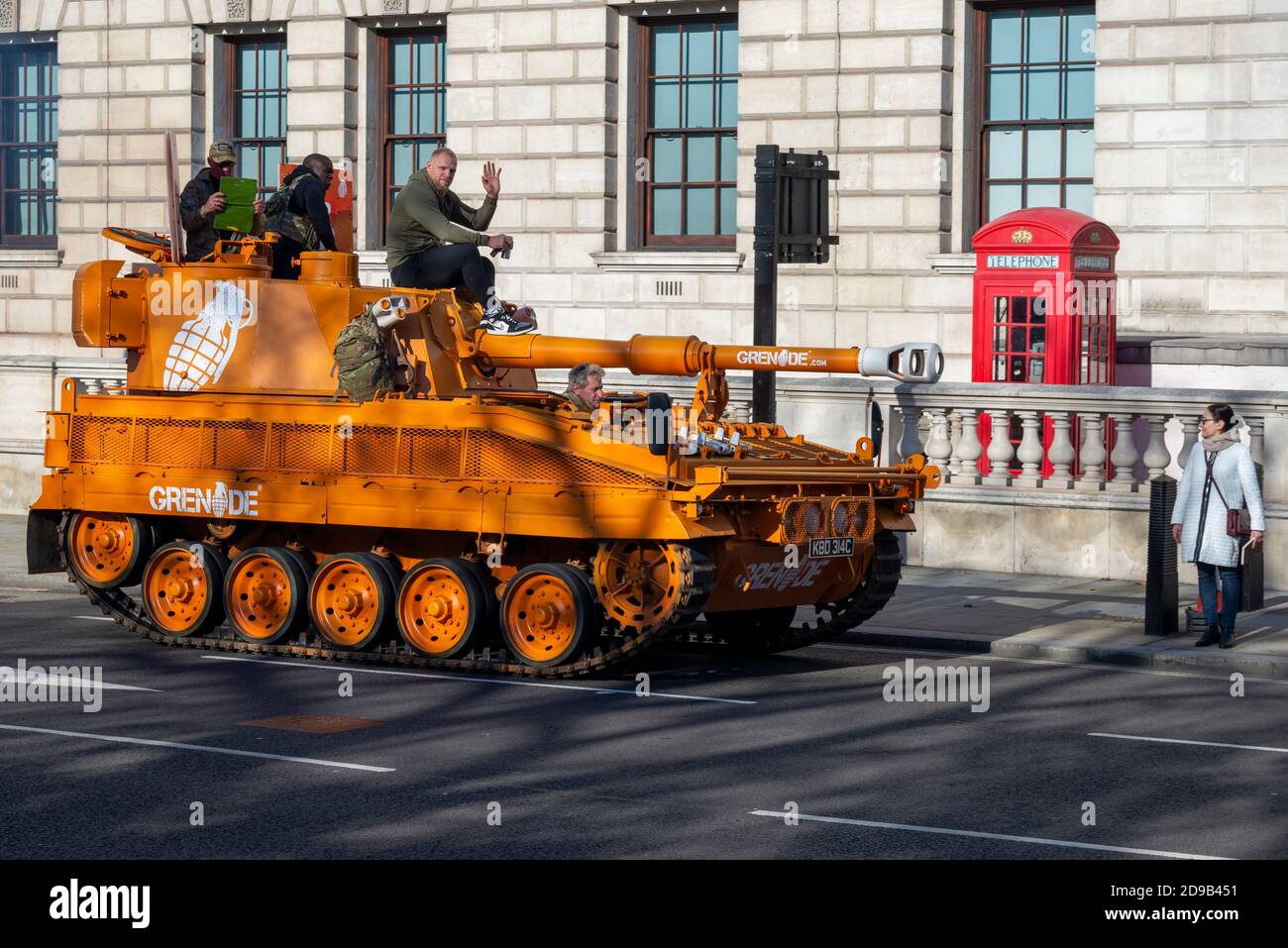 Westminster, London, UK. 4th Nov, 2020. An ex British Army Abbott tank (more correctly a self propelled gun) has been driving around Westminster and Parliament in protest at the closure of gyms during the COVID-19 Coronavirus lockdown. The orange de-mobbed Vickers Abbot FV433 armoured vehicle is advertising Grenade, a nutrition bar. Passing an iconic red telephone box and bystander Stock Photo
