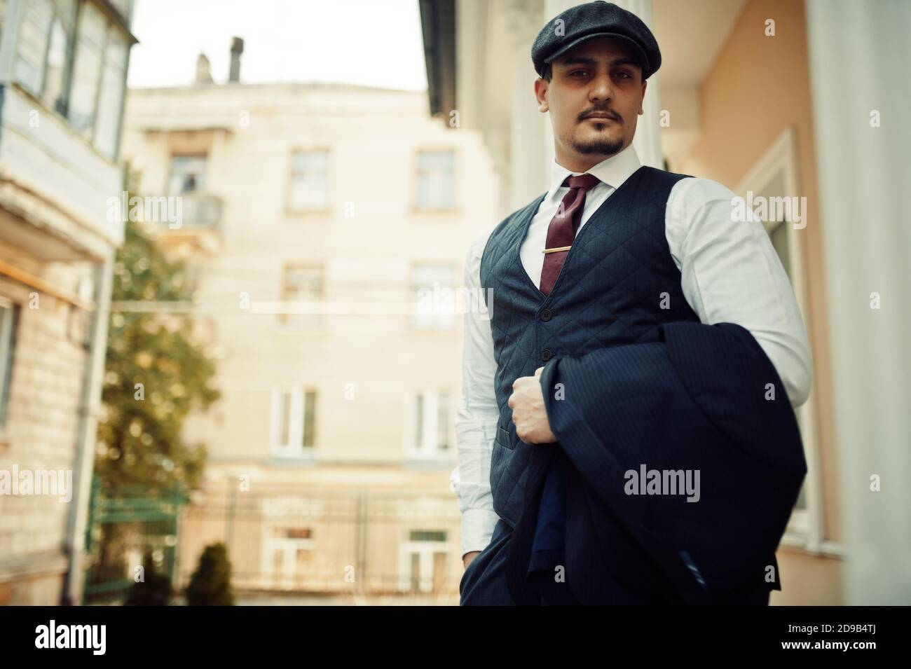 Portrait of retro 1920s english arabian business man wearing dark suit, tie and flat cap. Stock Photo