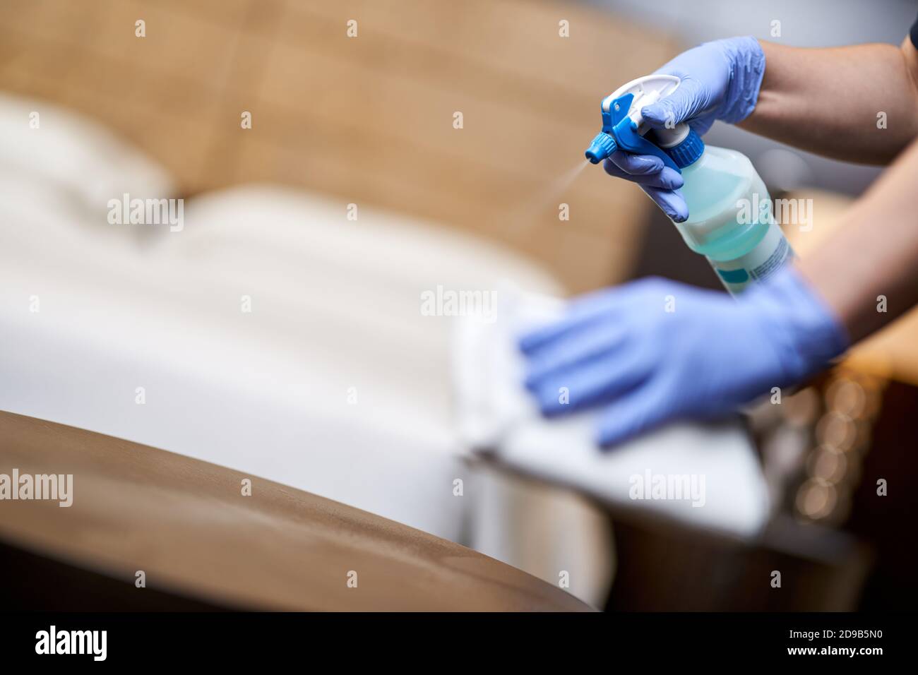 Cropped Photo Of Cleaning Lady In Blue Gloves Cleaning Table With Spray In Hotel Room 