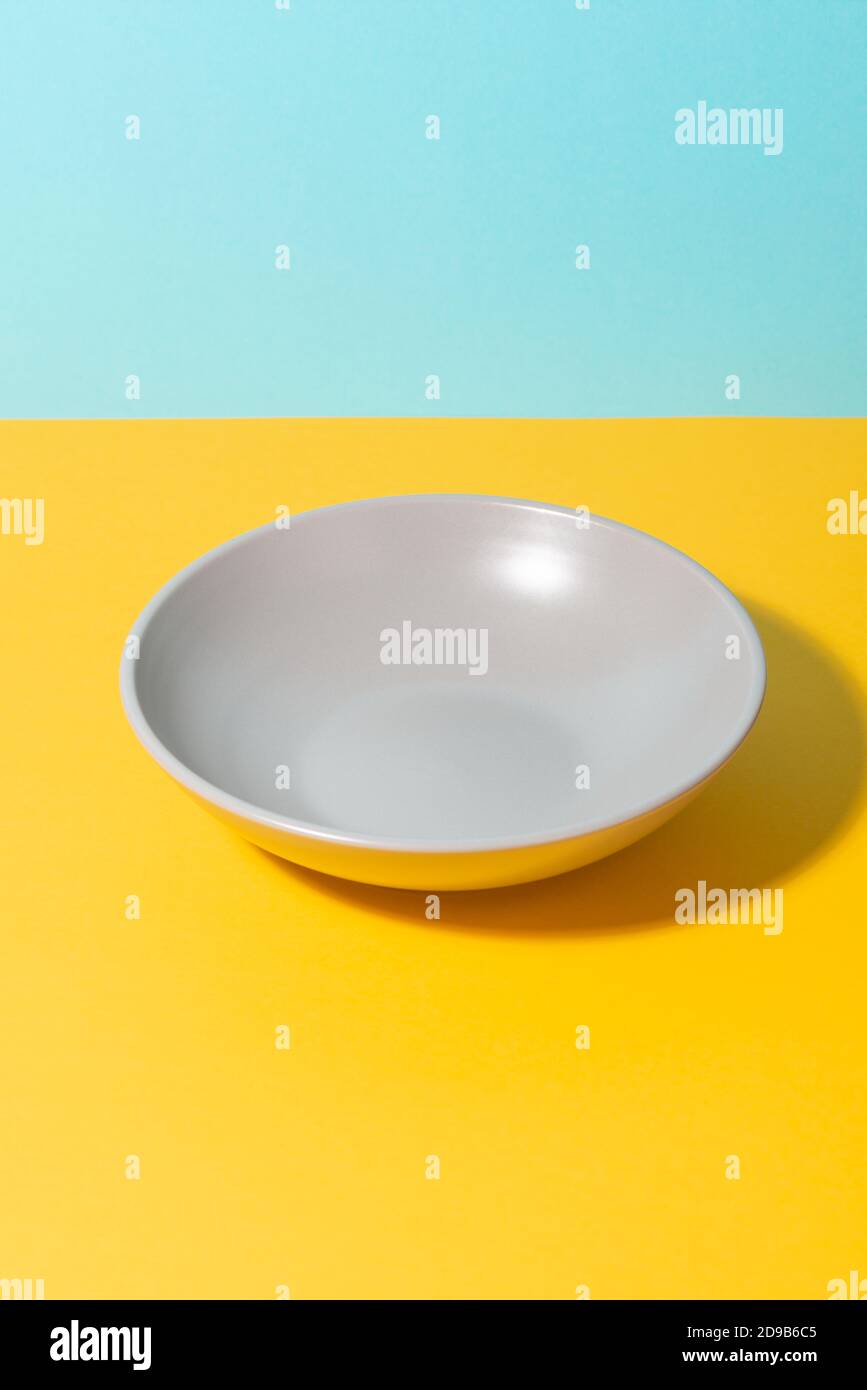 Deep gray plate on yellow and blue background Stock Photo