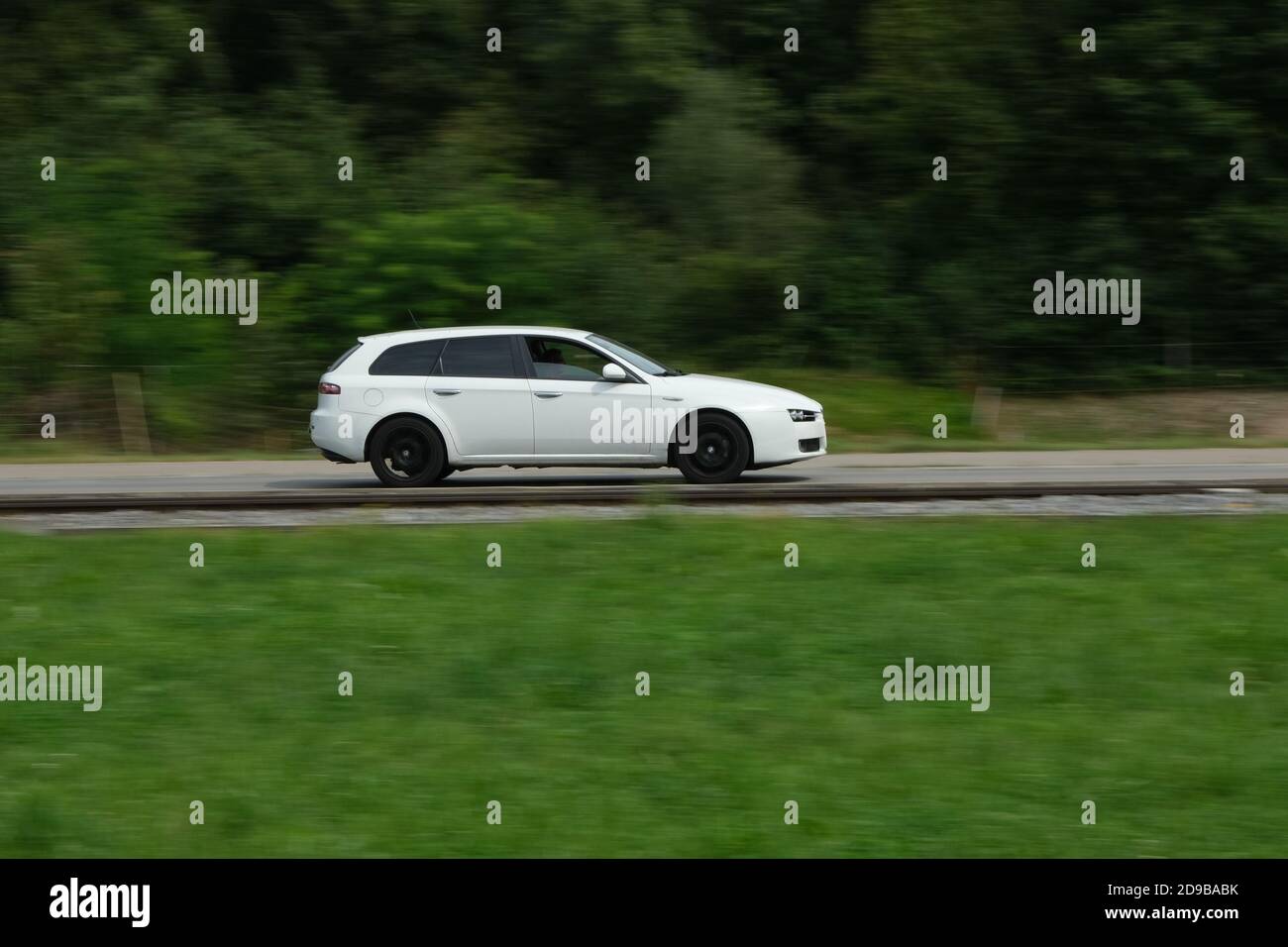 White car driving on the countryside asphalt road Stock Photo