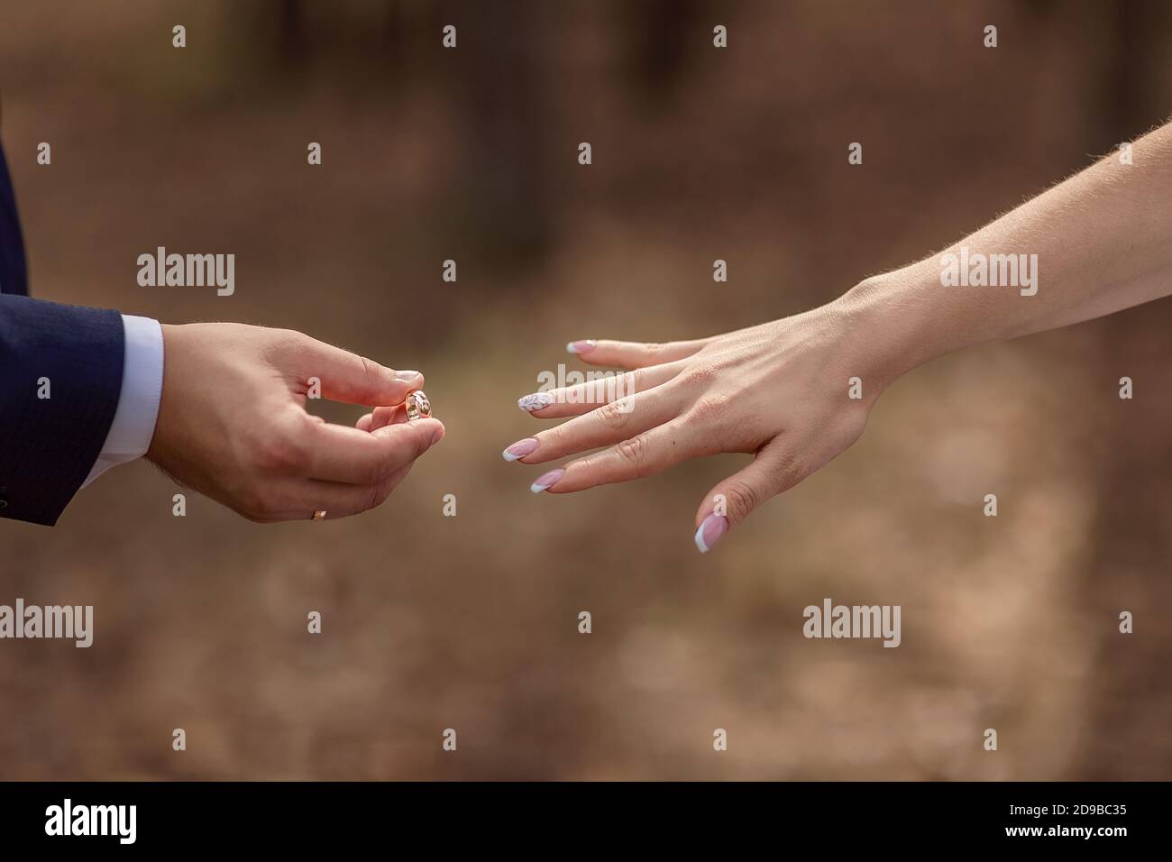 The groom (man) puts a ring on the left hand finger of the bride (girl