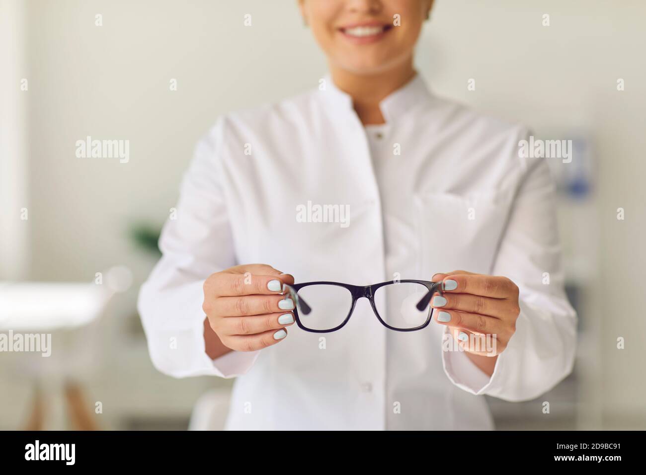 Professional vision specialist in a clinic or store holding a pair of glasses with new lenses. Stock Photo