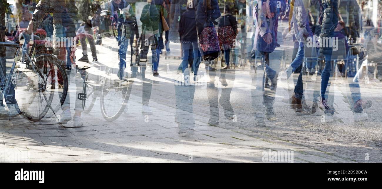 Abstract crowd of people walking without social distance on a shopping street in the city, multiple exposure and motion blur, panoramic format Stock Photo