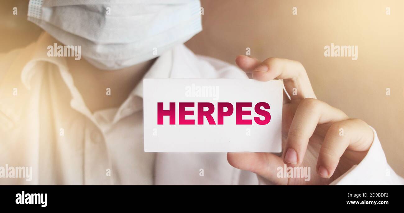 Doctor keeps a card with the name of the diagnosis Herpes. Selective focus. Medical concept Stock Photo