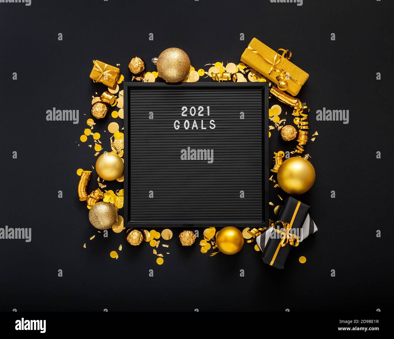2021 Goals text on black Letter Board in frame made of gold Christmas festive decor, gift boxes, confetti balls. New year 2021 goals, resolution check Stock Photo