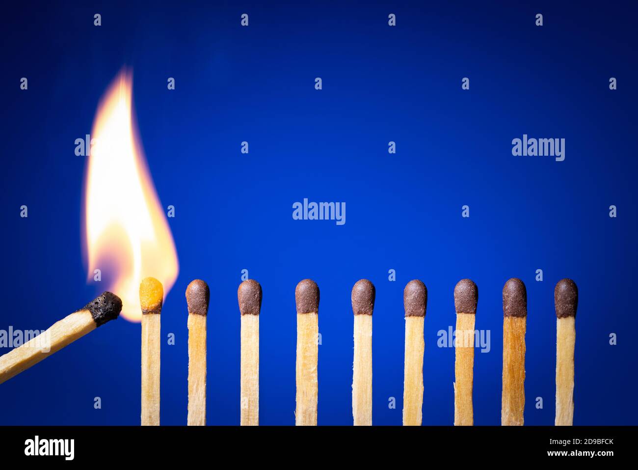 matches burning in a row on blue background. chain reaction Stock Photo