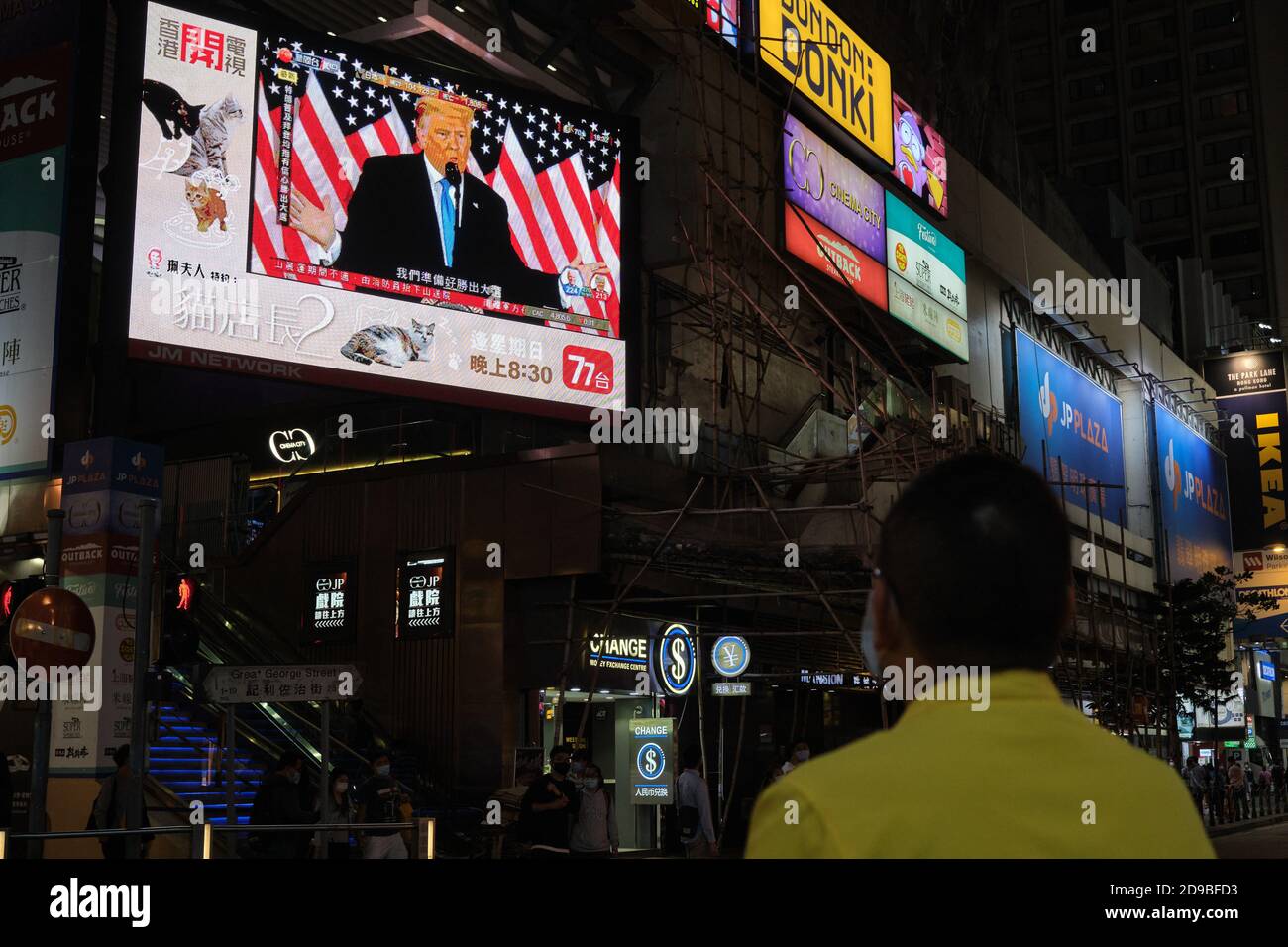 A man watches the Republican candidate Donald Trump speaking on a large screen broadcasting the live news report of the US Presidential election. Stock Photo